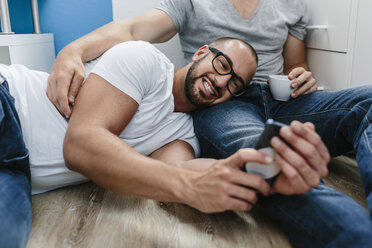 Homosexuelles Paar sitzt auf dem Boden und macht ein Selfie - MADF001166