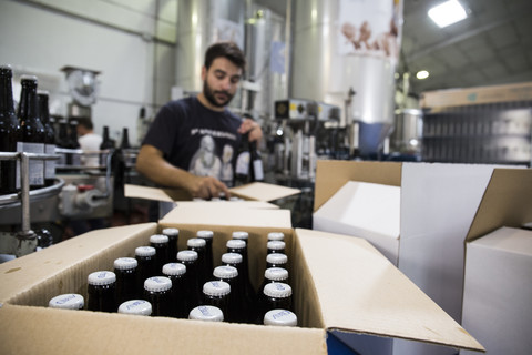 Mann bei der Arbeit in einer Bierabfüllanlage, lizenzfreies Stockfoto