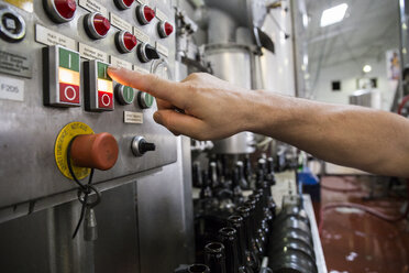 Mann drückt Knopf in einer Bierabfüllanlage - ABZF001092
