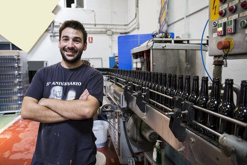 Man standing next to conveyor belt in bottling plant - ABZF001103