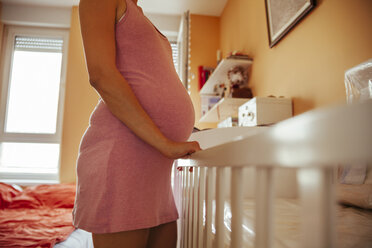 Schwangere Frau steht auf Babybettchen - ZEDF000302