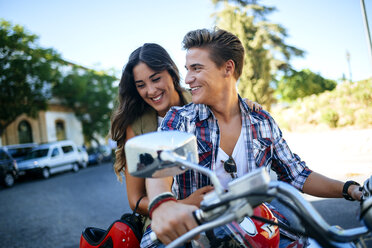 Glückliches junges Paar auf einem Motorrad - KIJF000729