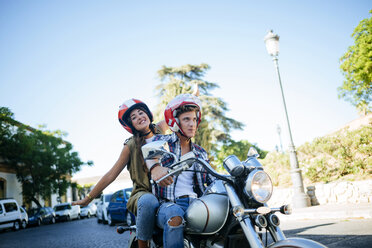 Happy young couple driving on a motorbike - KIJF000731