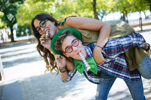 Junges Paar hat Spaß mit Partybläsern, Scherzbrillen und Mützen - KIJF000737
