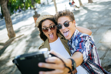 Young couple sticking out tongues while taking selfie with camera - KIJF000742