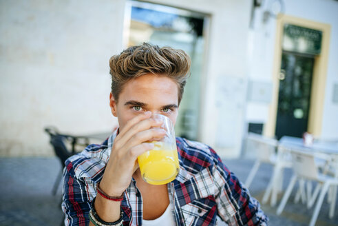 Junger Mann trinkt eine Orangeade - KIJF000760