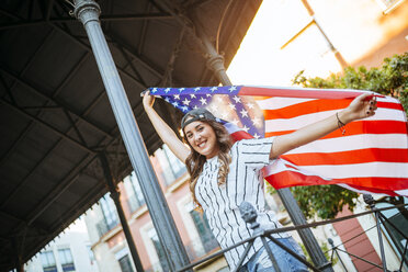 Portrait of smiling young woman posing with American flag - KIJF000767