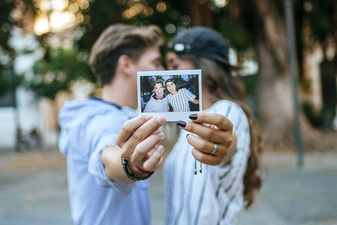 Junges verliebtes Paar, das ein Foto von sich selbst hält, lizenzfreies Stockfoto