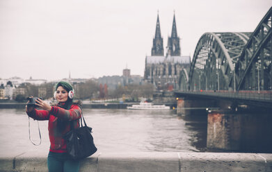 Deutschland, Köln, Frau mit Ohrenschützer macht Selfie mit Polaroidkamera - RTBF000279