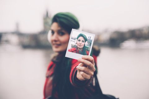 Deutschland, Köln, Frau zeigt Polaroid von sich, lizenzfreies Stockfoto