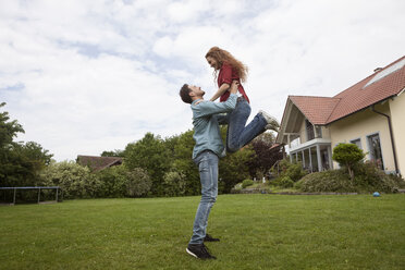 Happy man lifting up woman in garden - RBF005087