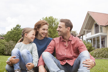 Smiling family sitting in garden - RBF005104