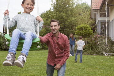 Vater schiebt Tochter auf Schaukel im Garten - RBF005107