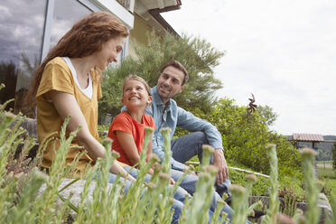 Lächelnde Familie im Garten sitzend - RBF005115