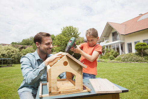 Vater und Tochter bauen ein Vogelhaus - RBF005117