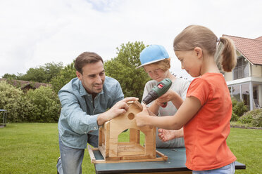 Father and children building up a birdhouse together - RBF005118