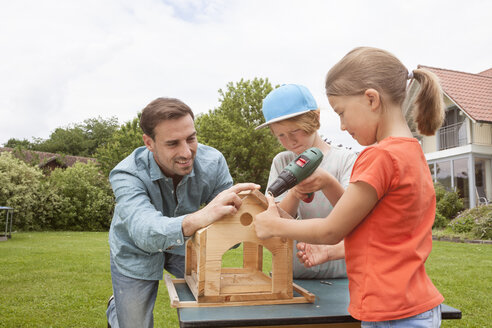 Vater und Kinder bauen gemeinsam ein Vogelhaus - RBF005118