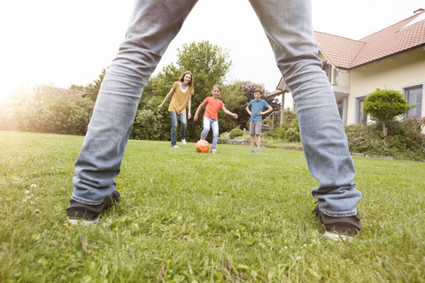 Family playing football in garden stock photo
