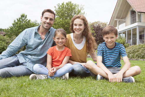 Porträt einer lächelnden Familie im Garten sitzend - RBF005124