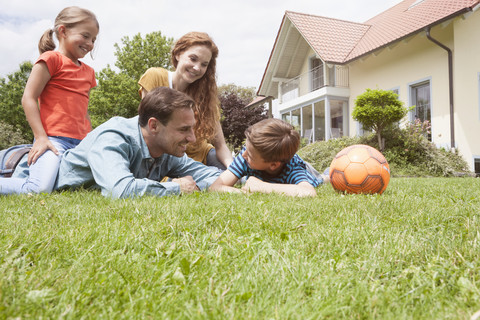 Lächelnde Familie im Garten mit Fußball, lizenzfreies Stockfoto