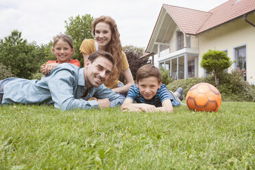 Porträt einer lächelnden Familie im Garten mit Fußball - RBF005132