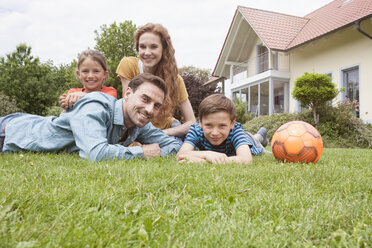 Portrait of smiling family in garden with football - RBF005132