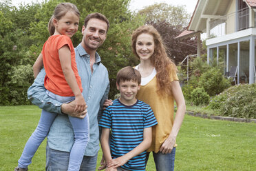 Porträt einer lächelnden Familie im Garten stehend - RBF005133