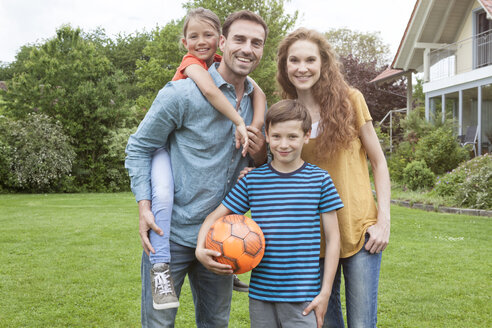 Porträt einer lächelnden Familie im Garten stehend - RBF005135