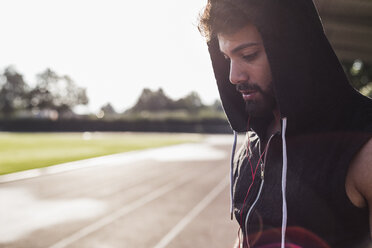 Young man wearing hooded top on tartan track - UUF008276