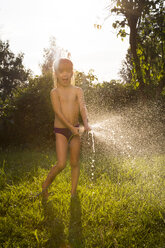 Kleines Mädchen spritzt Wasser mit Gartenschlauch - LVF005235