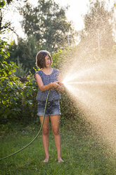 Mädchen spritzt Wasser mit Gartenschlauch - LVF005237