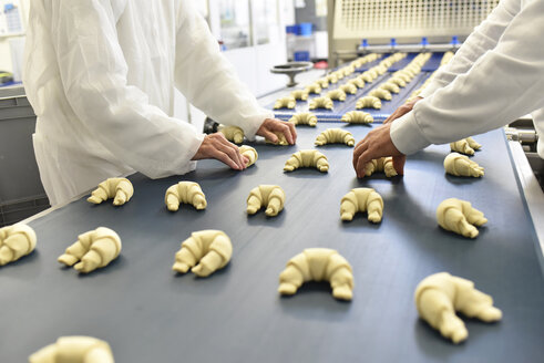 Workers at production line in a baking factory with croissants - LYF000534