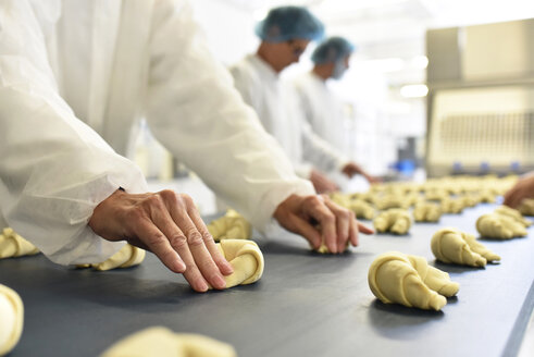 Workers at production line in a baking factory with croissants - LYF000535