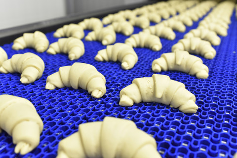 Produktionslinie in einer Backfabrik mit Croissants, lizenzfreies Stockfoto