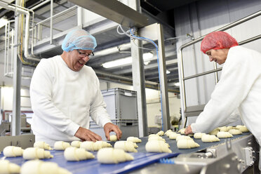 Arbeiter am Fließband in einer Backfabrik mit Croissants - LYF000544