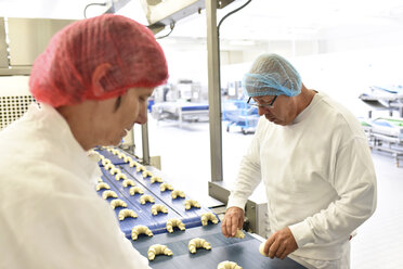Arbeiter am Fließband in einer Backfabrik mit Croissants - LYF000545