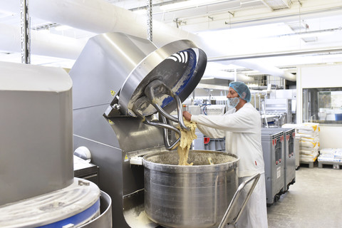 Arbeiter, der eine Teigknetmaschine in einer industriellen Bäckerei bedient, lizenzfreies Stockfoto