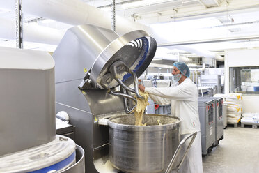 Arbeiter, der eine Teigknetmaschine in einer industriellen Bäckerei bedient - LYF000549