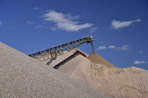 Conveyor belt pouring sand on heap in gravel pit stock photo