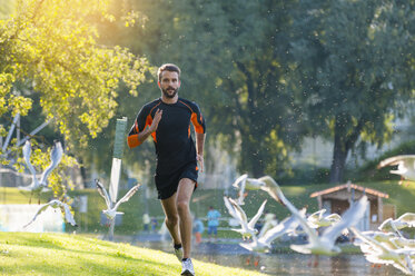 Man running at the riverside surrounded by seagulls - DIGF001063