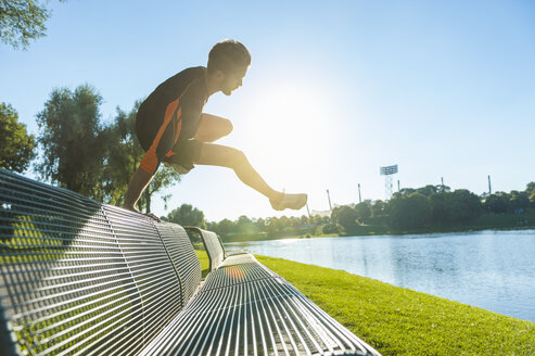 Athlet springt über Bank am Flussufer - DIGF001065