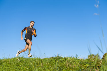 Man running on meadow under blue sky - DIGF001073
