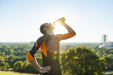 Sportler trinkt im Park aus einer Flasche - DIGF001078