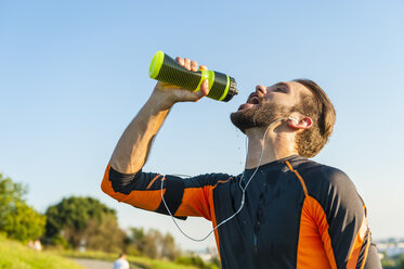 Sportler trinkt im Park aus einer Flasche - DIGF001079