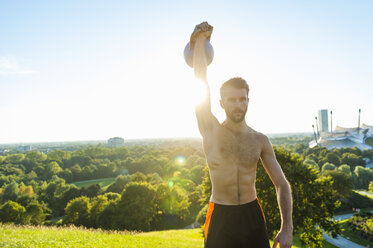Man exercising with kettlebell outdoors - DIGF001090