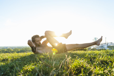 Mann macht Situps auf einer Wiese, lizenzfreies Stockfoto