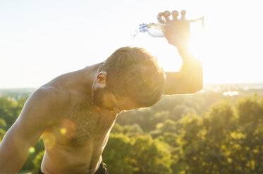 Barechested athlete pouring water over his head at sunset - DIGF001106