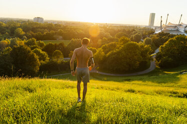 Sportler mit nacktem Oberkörper auf einer Wiese im Park bei Sonnenuntergang - DIGF001111