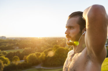 Barechested athlete with earbuds at sunset - DIGF001116