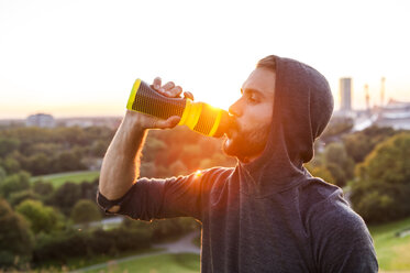 Sportler trinkt bei Sonnenuntergang aus einer Flasche - DIGF001130